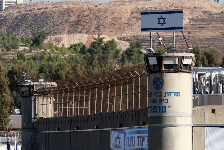 a prison turret and fence can be seen with an israeli flag